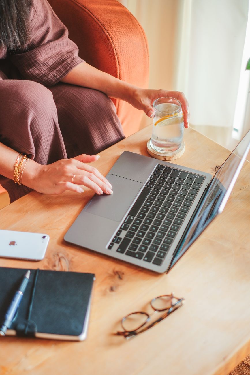 woman holding glass and using laptop